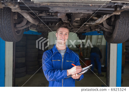 Mechanic preparing checklist under car Mechanic preparing checklist under car 6925324