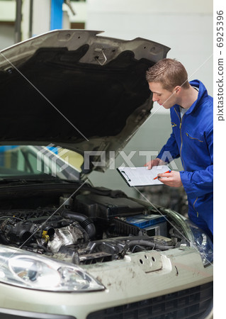 Mechanic checking car engine 6925396