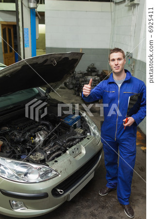 Mechanic by car showing thumbs up sign 6925411