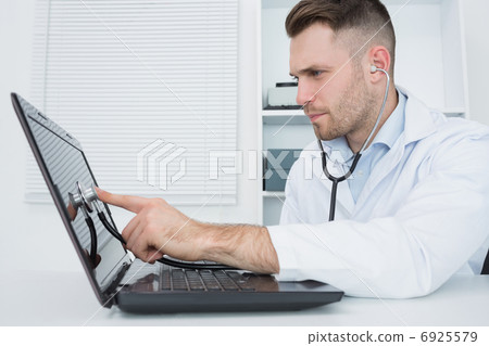 Hardware professional examining laptop with stethoscope Hardware professional examining laptop with stethoscope 6925579