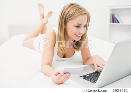 Casual young woman doing online shopping in bed Casual young woman doing online shopping in bed 6925581