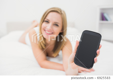 Portrait of woman showing smartphone in bed Portrait of woman showing smartphone in bed 6925583