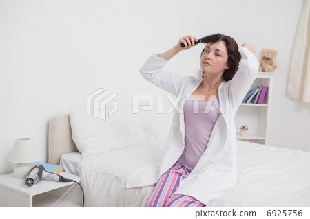 Young woman brushing hair in bed 6925756