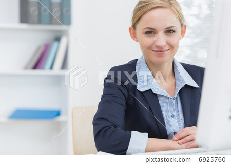 Confident business woman with computer at office desk 6925760