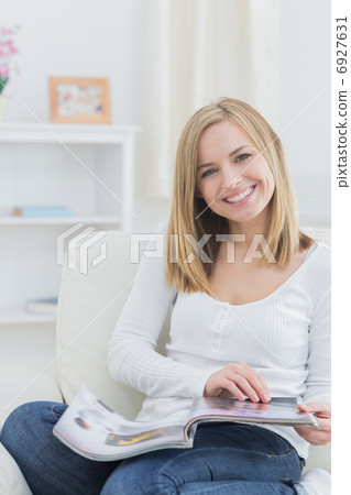 Portrait of happy woman with magazine at home 6927631
