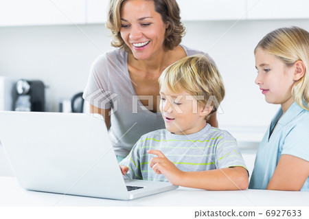 Mother using laptop with her children 6927633