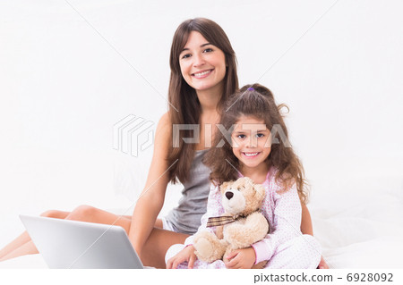 Smiling mother and daughter using laptop 6928092