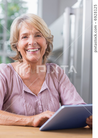 Happy mature woman using her digital tablet 6928125