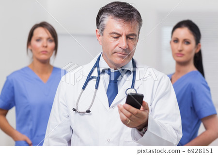 Doctor looking at phone with his team of nurses 6928151