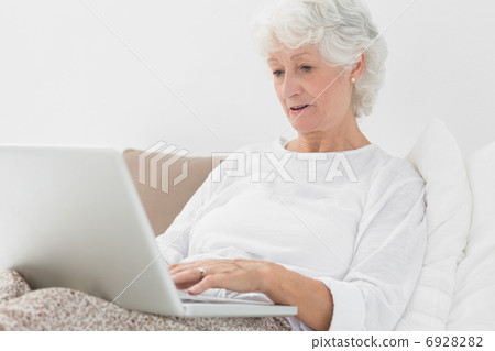 Old woman typing on her laptop 6928282
