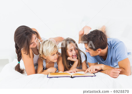 Family reading book on the bed Family reading book on the bed 6928870