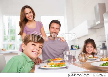 Family looking at the camera at dinner time Family looking at the camera at dinner time 6928922