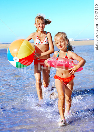 Children holding hands running on  beach. 6947150