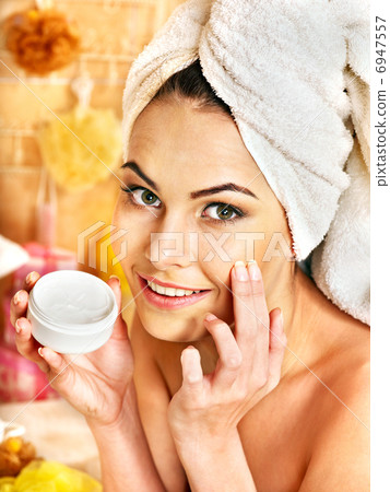 Woman applying moisturizer. 6947557
