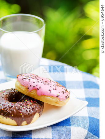 Fresh donuts and glass of milk on nature background Fresh donuts and glass of milk on nature background 6954644