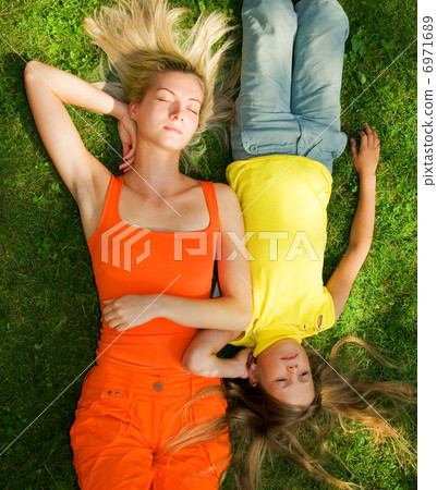 Two girls lying on a meadow 6971689