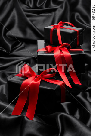 Black gift boxe with red satin ribbons and bows, over black satin Black gift boxe with red satin ribbons and bows, over black satin 6978280