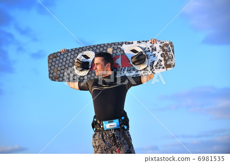 Portrait of a young kitsurf man at beach on sunset 6981535