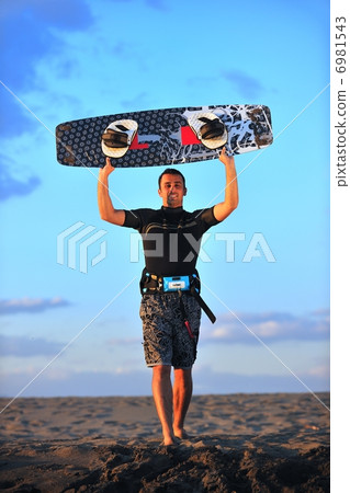 Portrait of a young kitsurf man at beach on sunset 6981543