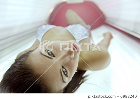 Beautiful young woman tanning in solarium 6988240
