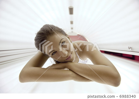 Beautiful young woman tanning in solarium Beautiful young woman tanning in solarium 6988340