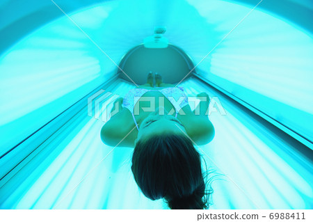 Beautiful young woman tanning in solarium 6988411