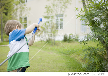 A boy shedding water in the garden A boy shedding water in the garden 6998498