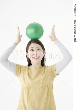 A woman holding a ball on her head 7000687