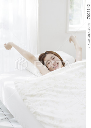 A woman stretching in bed 7003142