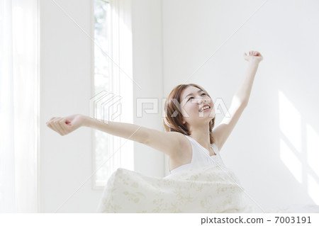 A woman stretching in bed 7003191