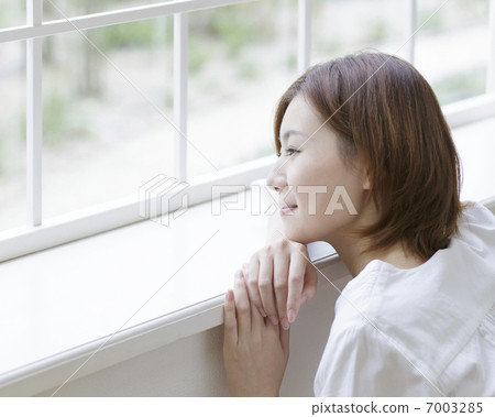 A woman who takes a cheek hand at the window side 7003285