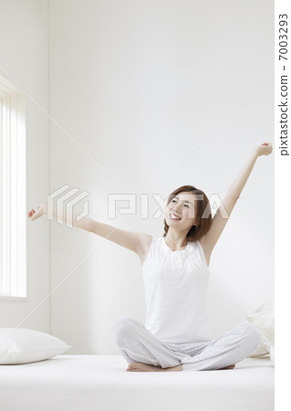 A woman stretching in bed 7003293