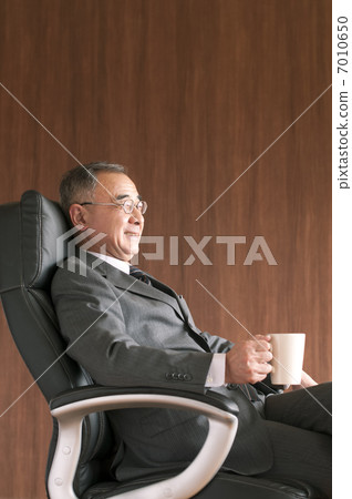 坐在椅子和有咖啡杯的商人 坐在椅子和有咖啡杯的商人 7010650