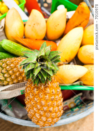 Selling tropical fruits and vegetables at market 7010978