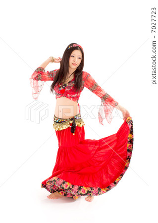 A young woman dancing belly dance passionately holding the edge of the skirt 7027723