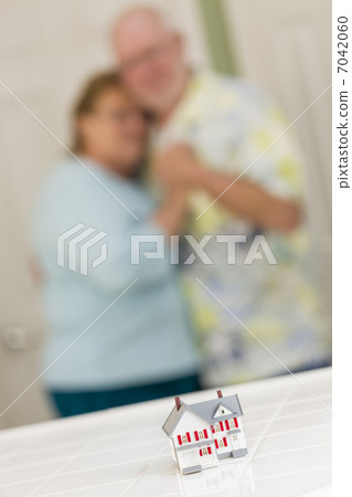 Senior Adult Couple Gazing Over Small Model Home on Counter 7042060