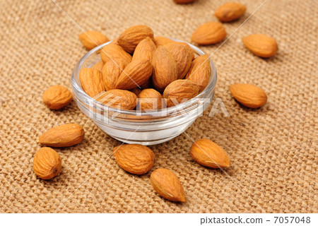 Dried almonds on glass bowl on canvas background 7057048