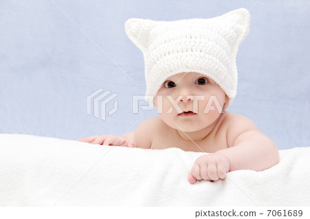 Beautiful baby in white hat lies on bed 7061689