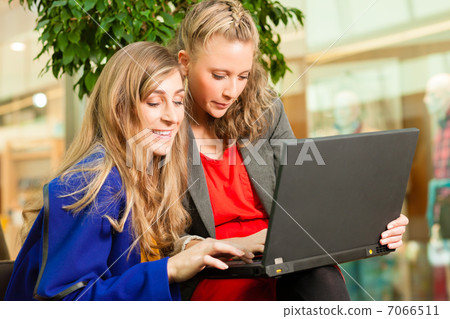 Two women shopping in mall with laptop Two women shopping in mall with laptop 7066511