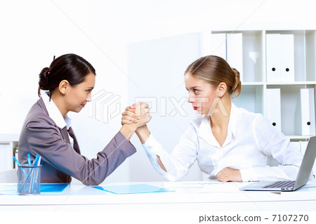 Young women arm wrestling in office Young women arm wrestling in office 7107270