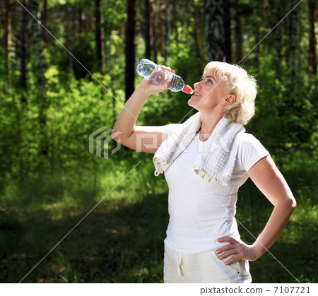 elderly woman after exercising in the forest 7107721