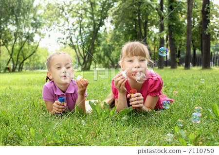 Little girl in the park blowing bubbles 7110750