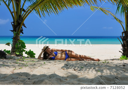 Woman at beach under palm tree 7128052