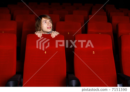 Young man in cinema watching movie Young man in cinema watching movie 7151390