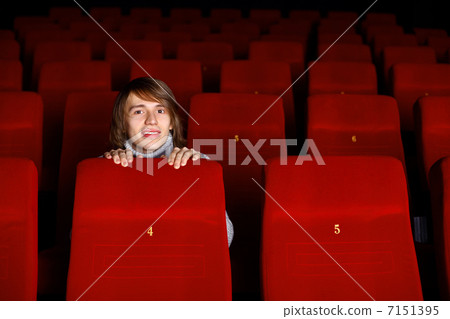 Young man in cinema watching movie Young man in cinema watching movie 7151395