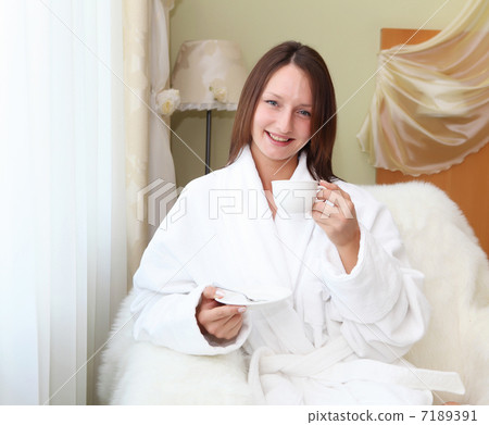 young woman in white robe drinking tea young woman in white robe drinking tea 7189391