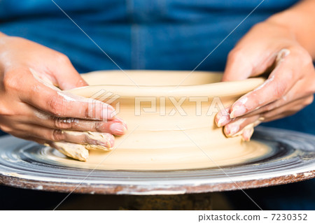 Potter creating clay bowl on turning wheel 7230352