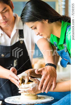 Potter creating clay bowl on turning wheel 7230355