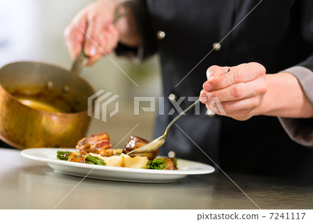 Chef in hotel or restaurant kitchen cooking 7241117