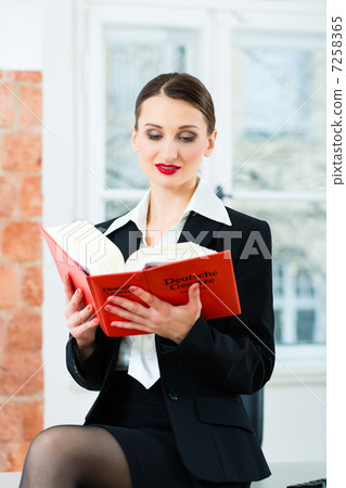 Lawyer in office reading law book 7258365